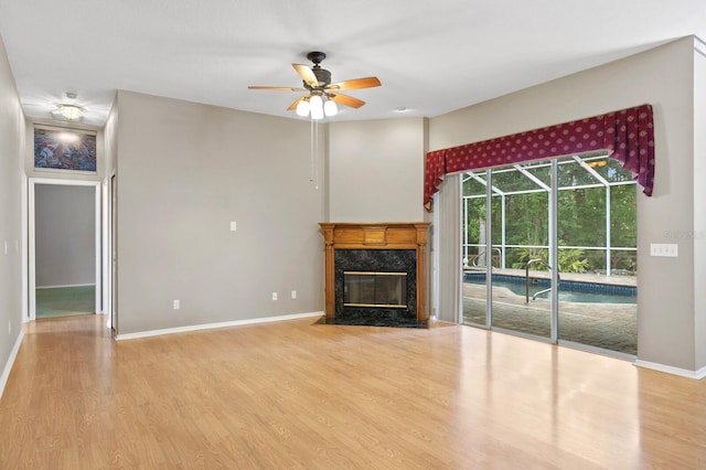 unfurnished living room with hardwood / wood-style floors, a high end fireplace, and ceiling fan