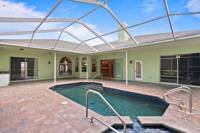 view of swimming pool featuring a patio area, glass enclosure, and ceiling fan