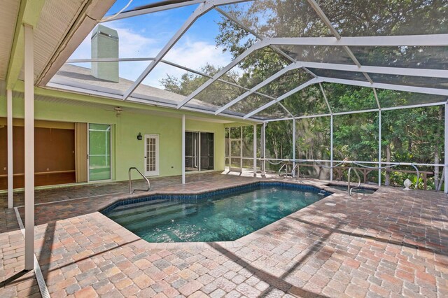 view of swimming pool featuring ceiling fan, glass enclosure, and a patio