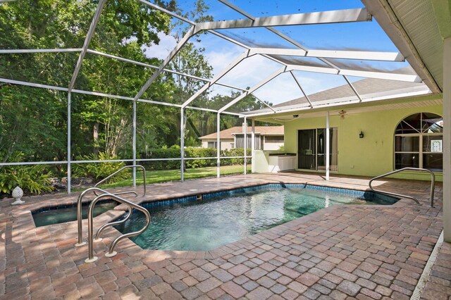 view of swimming pool featuring a patio, glass enclosure, and ceiling fan