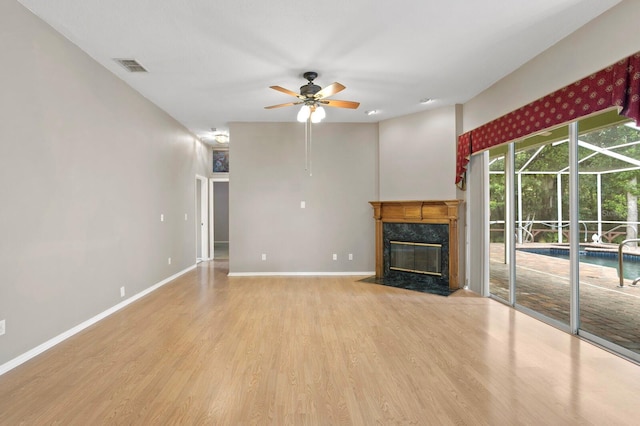 unfurnished living room featuring a high end fireplace, ceiling fan, and light wood-type flooring