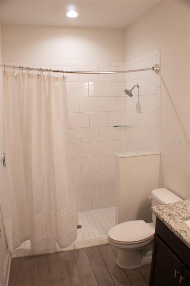 bathroom featuring wood-type flooring, a shower with curtain, toilet, and vanity