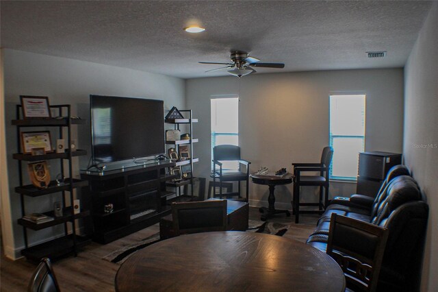 living room with a textured ceiling, wood-type flooring, and ceiling fan