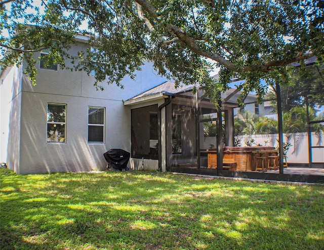 rear view of property with a yard and a hot tub