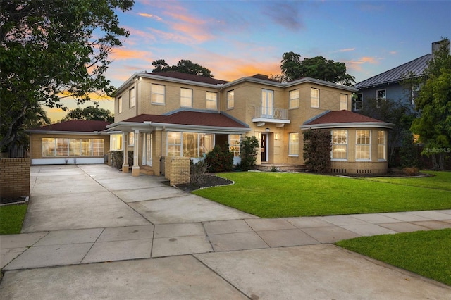 view of front of home featuring concrete driveway, brick siding, and a lawn