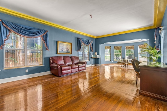 living room with crown molding, baseboards, and wood finished floors