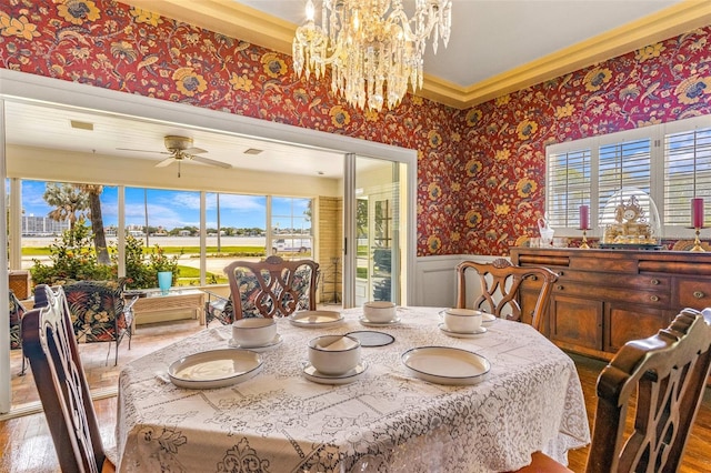 dining space with crown molding, ceiling fan with notable chandelier, and hardwood / wood-style floors