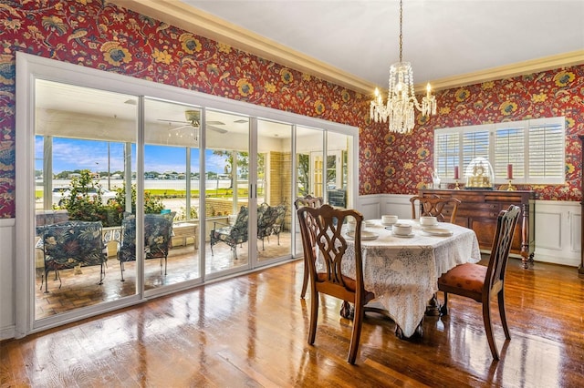 dining space with hardwood / wood-style flooring, ornamental molding, and ceiling fan with notable chandelier