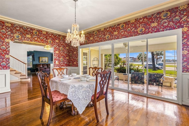 dining room featuring ornamental molding, wainscoting, wood finished floors, and wallpapered walls