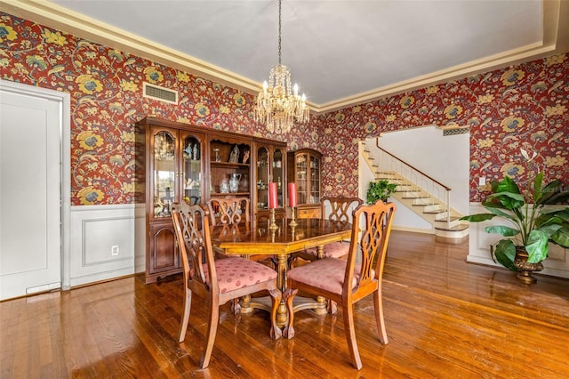 dining space with a tray ceiling, a notable chandelier, and hardwood / wood-style flooring