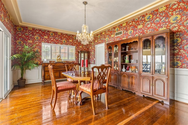 dining room featuring an inviting chandelier, ornamental molding, and hardwood / wood-style flooring