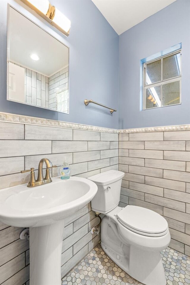 bathroom with tile floors, tasteful backsplash, toilet, and tile walls