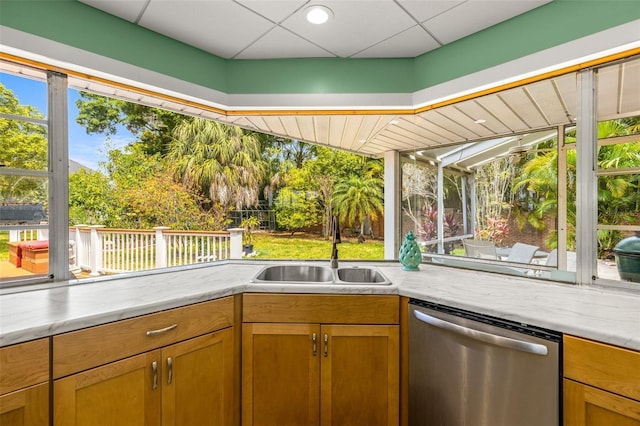 kitchen with a paneled ceiling, a sink, light countertops, brown cabinets, and dishwasher