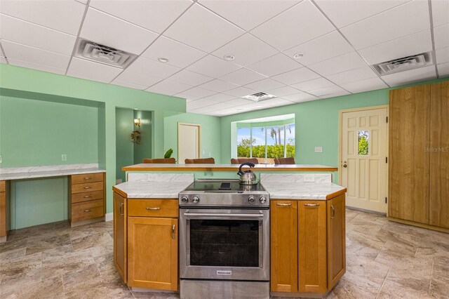 kitchen featuring a center island, electric stove, a paneled ceiling, and light tile floors