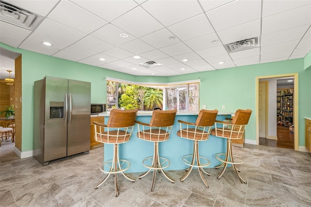 kitchen featuring stainless steel appliances, light tile flooring, and a drop ceiling