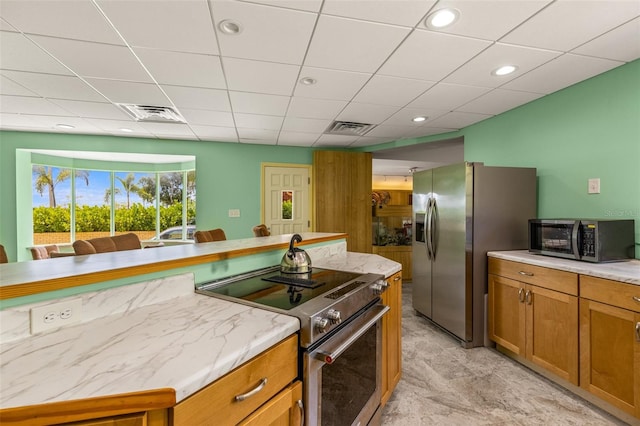 kitchen with light tile flooring, a paneled ceiling, and appliances with stainless steel finishes