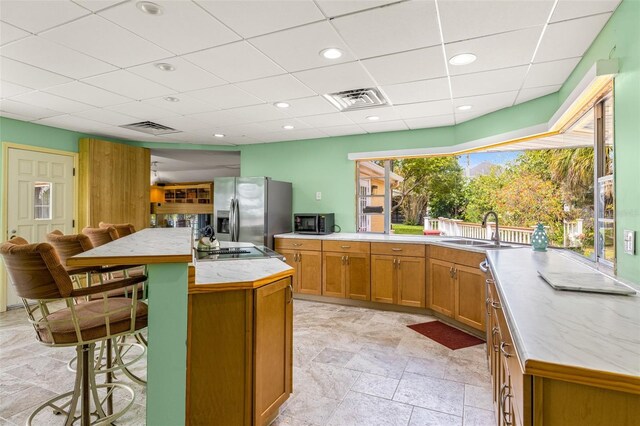 kitchen featuring appliances with stainless steel finishes, an island with sink, a breakfast bar area, sink, and light tile floors