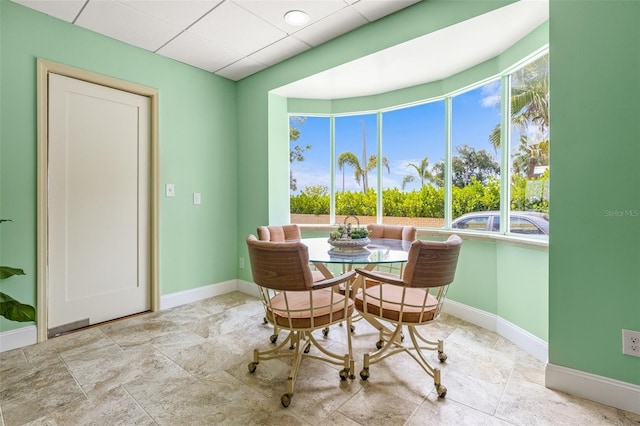 dining area featuring a paneled ceiling and baseboards