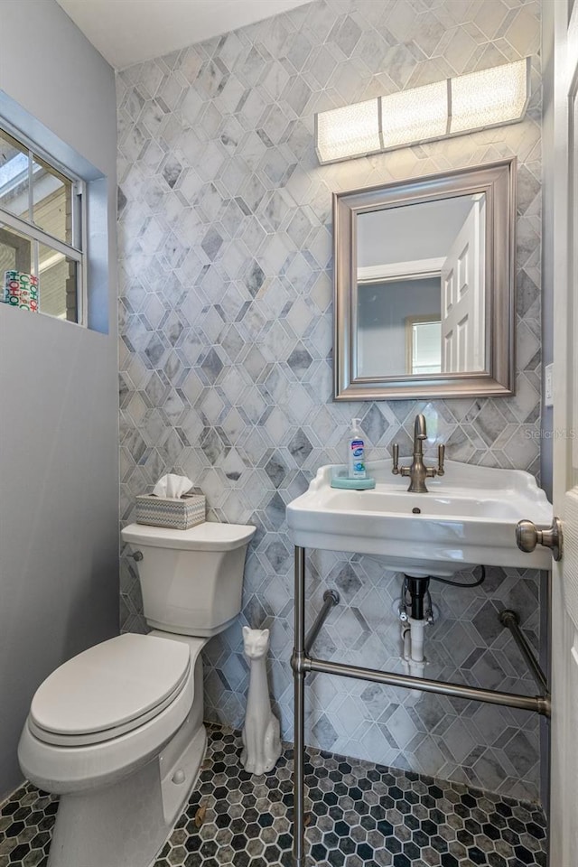 bathroom featuring tile flooring, tile walls, and toilet