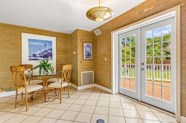 dining room with french doors, light tile flooring, and wooden walls