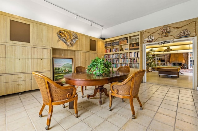 dining room featuring track lighting, light tile patterned flooring, and wooden walls