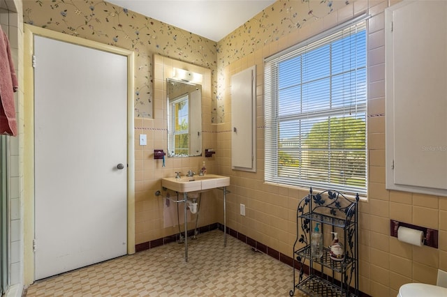 bathroom featuring a healthy amount of sunlight, sink, tile walls, and tile floors