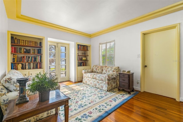 sitting room with crown molding, hardwood / wood-style flooring, and built in shelves