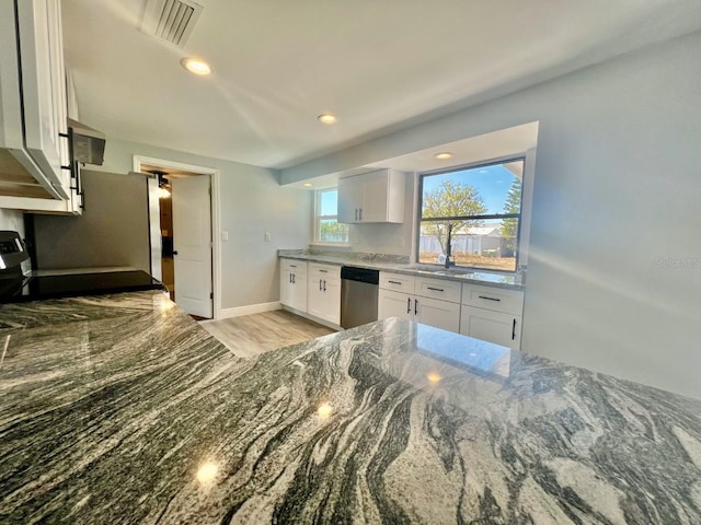 kitchen featuring stainless steel dishwasher, dark stone counters, light hardwood / wood-style flooring, white cabinets, and range