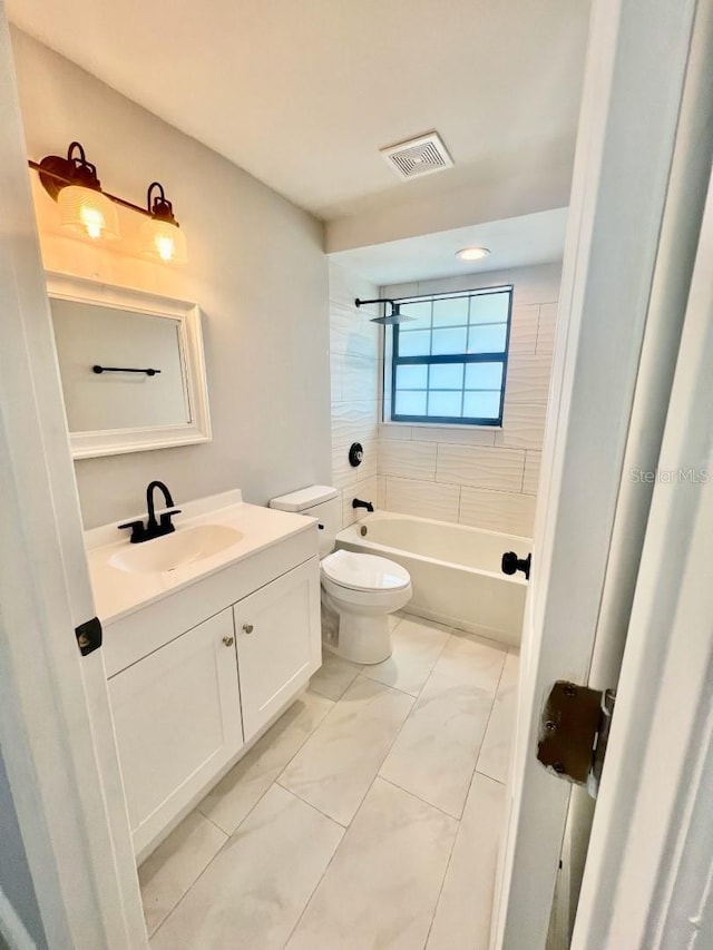 full bathroom with vanity, tiled shower / bath combo, and toilet