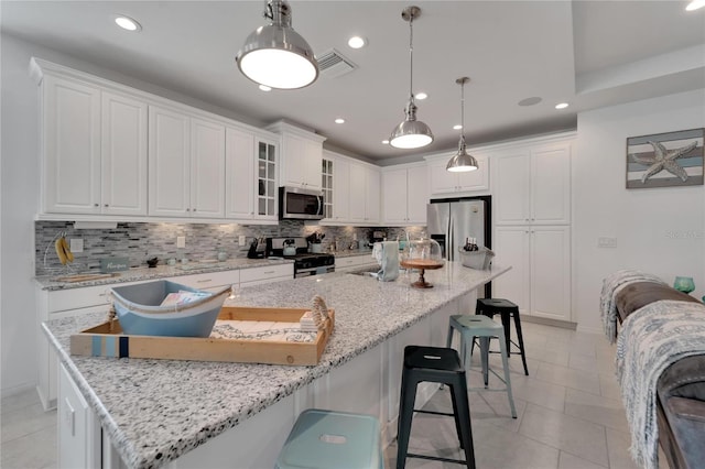 kitchen with white cabinetry, pendant lighting, light stone counters, and appliances with stainless steel finishes