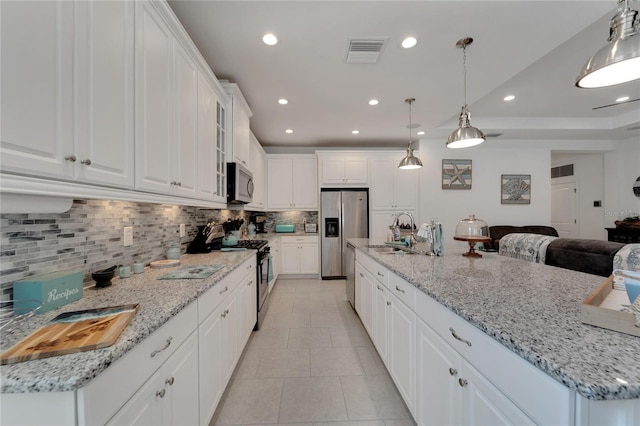 kitchen featuring hanging light fixtures, decorative backsplash, white cabinetry, appliances with stainless steel finishes, and sink