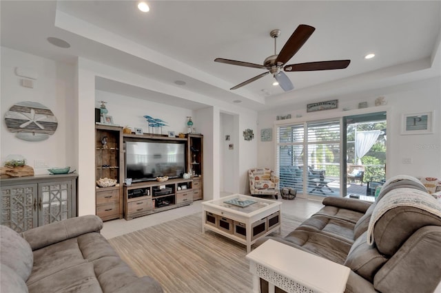 living room with ceiling fan and a tray ceiling