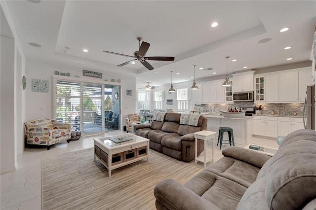 tiled living room featuring ceiling fan and a raised ceiling