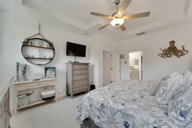 bedroom with ceiling fan, ensuite bath, and a raised ceiling