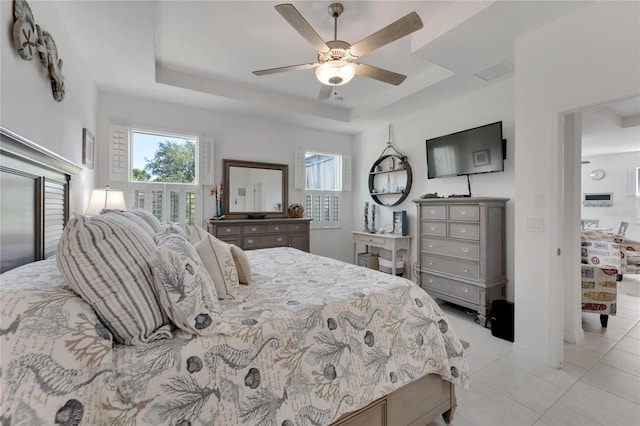 bedroom with light tile patterned flooring, ceiling fan, and a tray ceiling