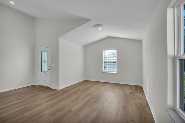 additional living space with a textured ceiling, light wood-type flooring, and lofted ceiling