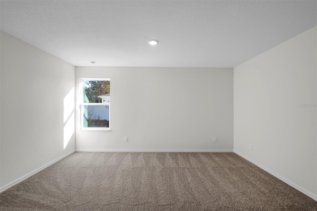 empty room with carpet floors and a textured ceiling