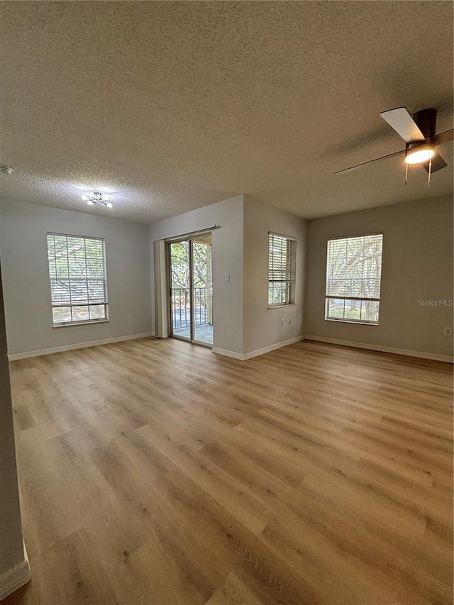 empty room with a textured ceiling, ceiling fan, and light wood-type flooring