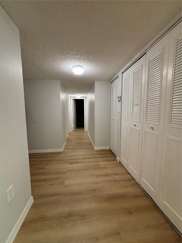 corridor with light hardwood / wood-style flooring and a textured ceiling