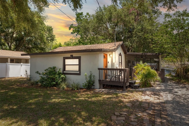 back house at dusk featuring a yard and a wooden deck