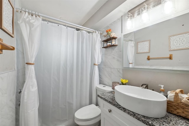 bathroom with toilet, a shower with shower curtain, vanity, and tile walls