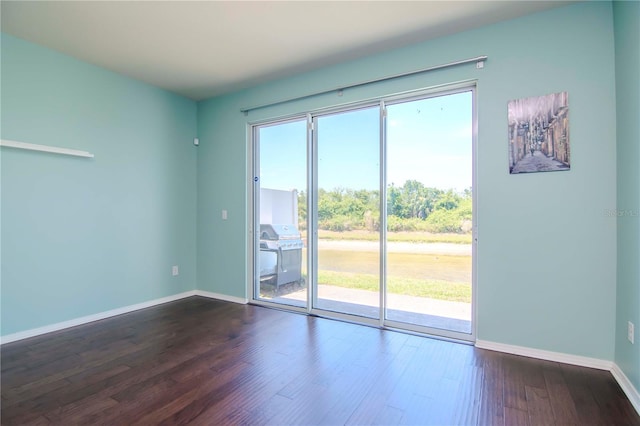 spare room with plenty of natural light and dark wood-type flooring