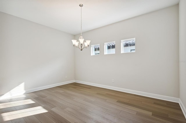 empty room with hardwood / wood-style floors and an inviting chandelier