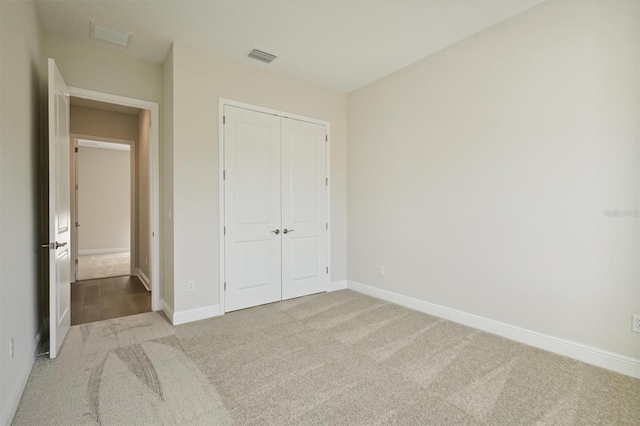 unfurnished bedroom featuring light colored carpet and a closet