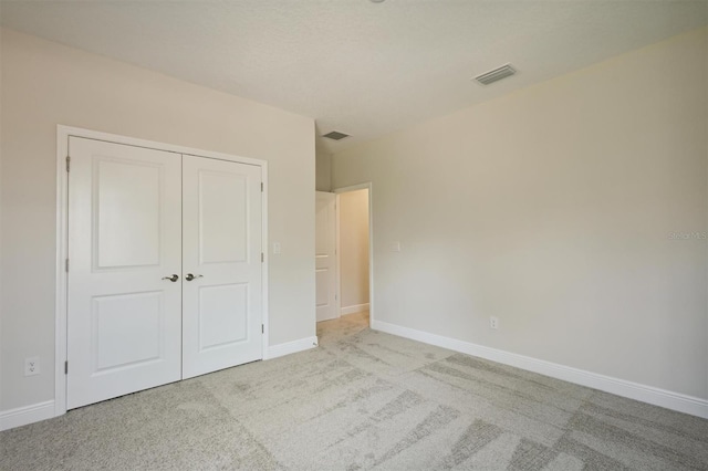 unfurnished bedroom featuring light colored carpet and a closet