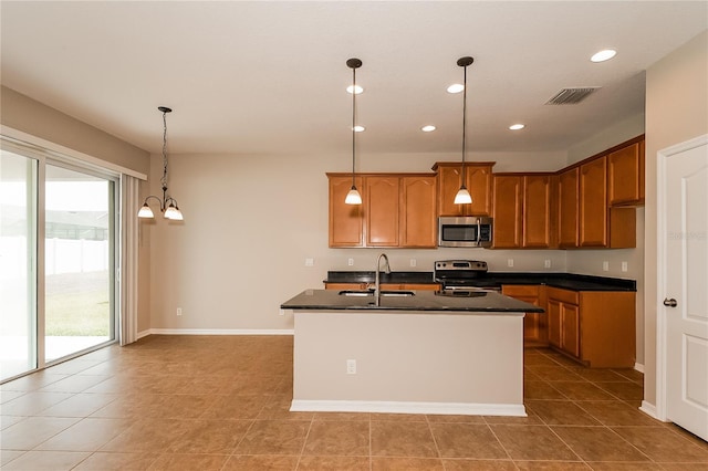 kitchen featuring a healthy amount of sunlight, sink, stainless steel appliances, and a center island with sink