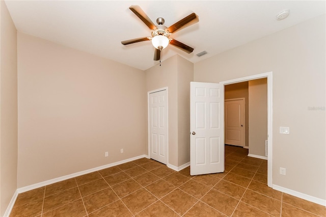 unfurnished bedroom with dark tile patterned flooring and ceiling fan