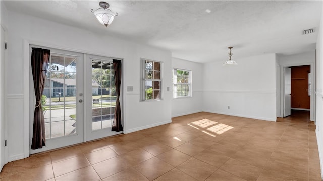 doorway to outside featuring a healthy amount of sunlight, light tile patterned floors, a textured ceiling, and french doors