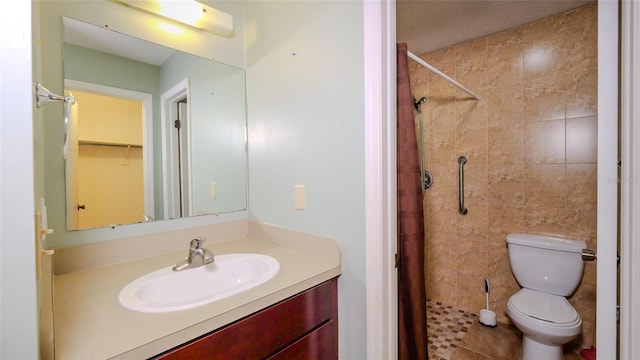 bathroom featuring tiled shower, vanity, and toilet