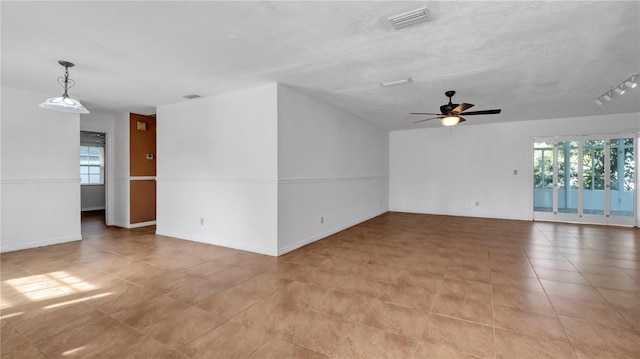 spare room featuring ceiling fan, a healthy amount of sunlight, and a textured ceiling